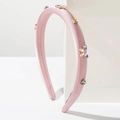 Détail du serre-tête en satin rose avec strass colorés et nœud en cristal sur pierre - Rose