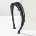 Detalle de diadema negra con cuentas y estructura de peine sobre base de mármol - Negro