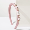 Detail of pink satin headband with inlaid pearls and sparkling crystals on geometric stand - Pink