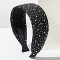 Detalle de una diadema negra ancha con diamantes de imitación sobre un soporte blanco - Color AB