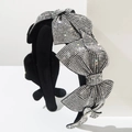 Close-up of black headband with four layered bows encrusted with sparkling silver rhinestones - White