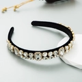 Close-up of Baroque headband with clear crystals on black velvet base and gold metal - White