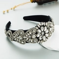 Close-up of wide black headband with intricate floral pattern in sparkling rhinestones - White
