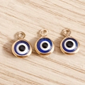 Detailed macro view of three golden evil eye charms on a light wood texture background - 60Pcs Set / Gold