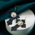 Detail van vintage leren kruis oorbellen met kleurrijke edelsteen en kristalaccenten - Zwart