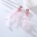 Dettaglio di orecchini di piume rosa con fiore di cristallo su pietra bianca pura - Rosa