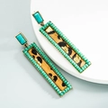 Close-up of geometric earrings with leopard print leather and turquoise bead border - Green
