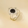 Dettaglio anello in acciaio argento con pietra nera su sfondo in raso champagne - Nero Argentato (J770-S-B)