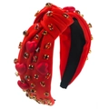 Detalle de una diadema barroca roja con strass brillantes y detalles de corazones - Corazón de Perla