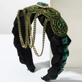 Detailed macro view of black braided velvet headband with emerald green gemstones and gold fringe - Green