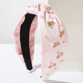 Dettaglio del cerchietto rosa con nodo, perle bianche e scritta LOVE in oro lucido - Rosa
