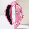 Detailopname van roze stoffen haarband met fonkelende steentjes en glanzende hartjesdecoraties - Roze