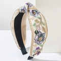 Gros plan détaillé du serre-tête en satin brodé avec des motifs floraux violets élégants - Violet