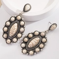 Detailed macro view of vintage silver earrings with white marble texture stones and ornate metalwork - Howlite
