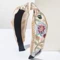 Détail d'un serre-tête en tissu crème avec broderies florales et fils dorés élégants - Rouge & Bleu