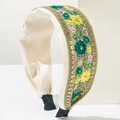 Detailopname van een crème hoofdband met bloemenborduursels en gouden pailletten - Groen