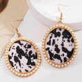 Close-up of leopard print leather earrings with faux pearl trim and golden metal frame - Black and White