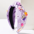 Detail of purple knotted headband featuring candy resin charms and white pearls on white stone - Purple