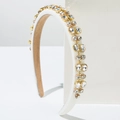 White padded headband with sparkling crystals and satin finish on a minimalist display - Beige