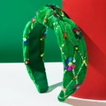 Détail d'un serre-tête en velours vert orné de paillettes colorées et d'un nœud élégant - Vert
