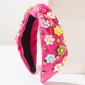 Dettaglio di un cerchietto rosa con nodo, fiori 3D colorati e strass luminosi decorativi - Oro Rosa