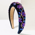 Détail de fleurs en strass étincelants et chaîne dorée sur serre-tête en velours bleu - Violet