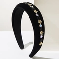 Detailed close-up of a black velvet headband with gold flowers and sparkling rhinestones - Black