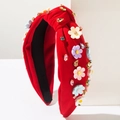 Détail d'un serre-tête noué rouge avec des fleurs en résine et des strass colorés - Rouge