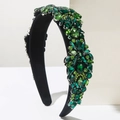 Detailed view of green rhinestones and emerald crystals on a luxury black headband - Green