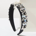 Macro shot of baroque headband with crystals and pearl bow on white platform - White