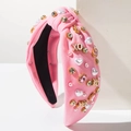 Detail eines rosa Knotenstirnbands mit Strasssteinen, Perlen und XO Metallbuchstaben - Rosa