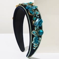 Baroque padded headband with blue velvet, crystals, and gold flower accents on white pedestal - Blue