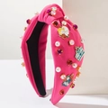 Detail van roze haarband met parels, kristallen en emaille bedeltjes met MOM-thema - Rozerood