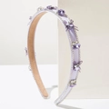 Détail d'un serre-tête violet avec cristaux et nœud en tulle sur support blanc - Violet