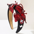 Detail van rode strass vlinderornamenten op een luxe zwarte satijnen hoofdband - Rood