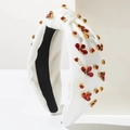Dettaglio del cerchietto bianco a nodo con strass rossi e montature dorate - Bianco
