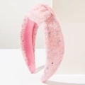 Dettaglio di un cerchietto in maglia rosa con nodo e paillettes colorate effetto puntinato - Peluche Rosa
