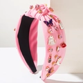 Détail d'un serre-tête en tissu rose avec des cœurs en strass et breloques musicales - Rose