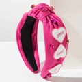 Détail d'un serre-tête rose avec strass et écussons en forme de cœur brodés LOVE - Or Rose
