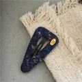 Close-up of knit fabric triangle hair clip with handmade gold metal logo detail - Triangle Knitted Snap Clip (300-B263) / Navy Blue