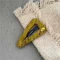 Detailed macro view of yellow-green knit triangle hair clip with golden metal handmade tag - Triangle Knitted Snap Clip (300-B263) / Yellow