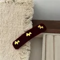 Primo piano di un fermaglio per capelli in velluto bordeaux con tre ciondoli a cucciolo dorati - Rosso Vino Ornamento Triplo (Stile Agatha) / Borgogna