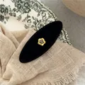 Macro shot of black velvet oval hair clip with gold flower and rhinestone detail - Patterned Black