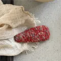Macro di un fermaglio per capelli in lana rossa con dettagli in tessuto a maglia grossa - Stile Goccia d'Acqua