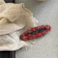 Dettaglio di un fermaglio per capelli BB ovale in tweed rosso e grigio su tessuto - Stile Ovale