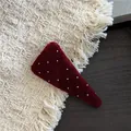 Close-up of a burgundy velvet triangular hair clip with white polka dots on a wooden plate - B5.2 Triangle Polka Dot (Red Snap Clip)