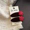 Detailaufnahme von zwei roten Strickblumen-Haarspangen mit Kristallen auf Samtbasis - Kaffee Haarspange (Rote Blume)