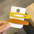 Minimalist geometric hair clips in bright yellow and orange resin on a display card - Orange + Yellow