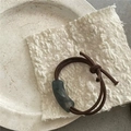 Détail d'un élastique à cheveux marron avec perle en résine mate gris foncé sur assiette - Vert Foncé (Élastique à Perles Courbes)