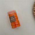 Detail of orange elastic hair ties in a clear cylindrical jar with a branded logo label - Orange